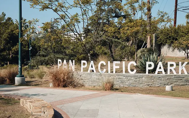 Sign of Pan Pacific Park with surrounding greenery and pathway.