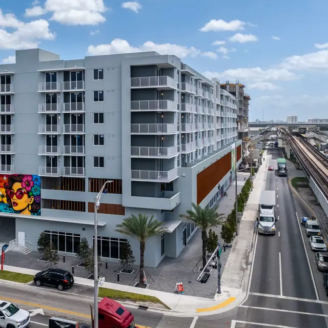 Modern multi-story building with colorful mural and adjacent roadway.