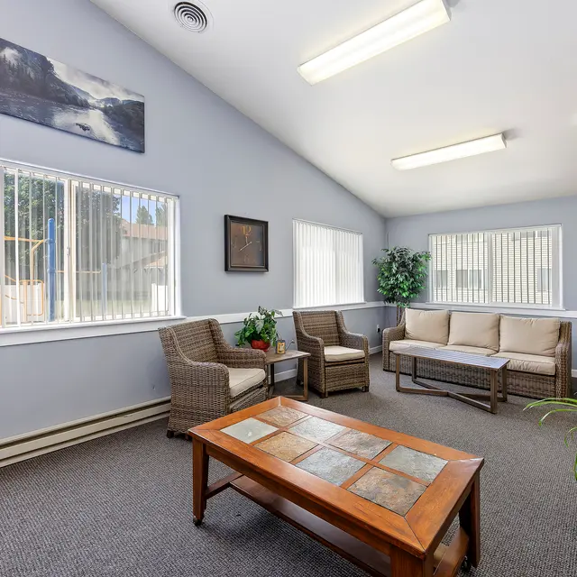 Cozy Lounge Area A well-lit, cozy lounge area with beige furniture, a wooden coffee table, and plants. Bright windows allow natural light to fill the space, creating a welcoming atmosphere.