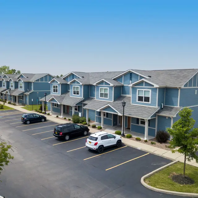Aerial view of a residential complex with blue multi-unit homes and parking spaces.