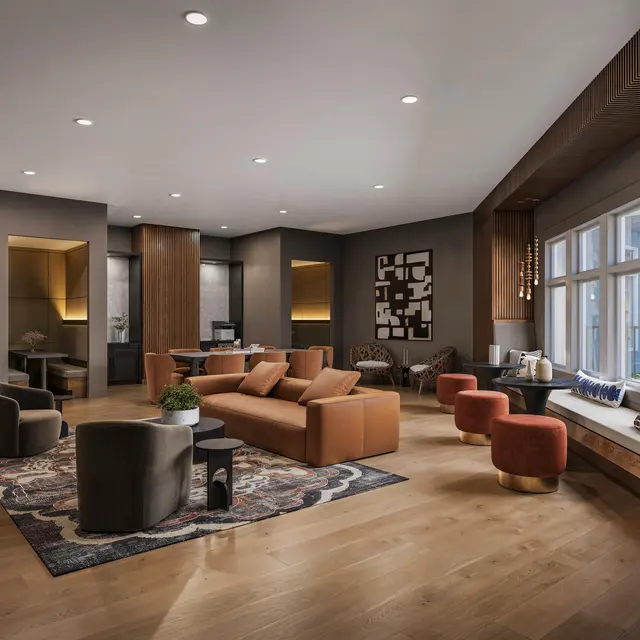 A modern living room featuring brown and orange furnishings, large windows with seating, and a patterned rug on a wooden floor.