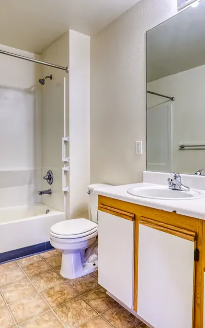 A clean and simple bathroom featuring a tub-shower combination, a vanity with a sink, and a toilet. The walls are painted in neutral colors and the floor has tile.