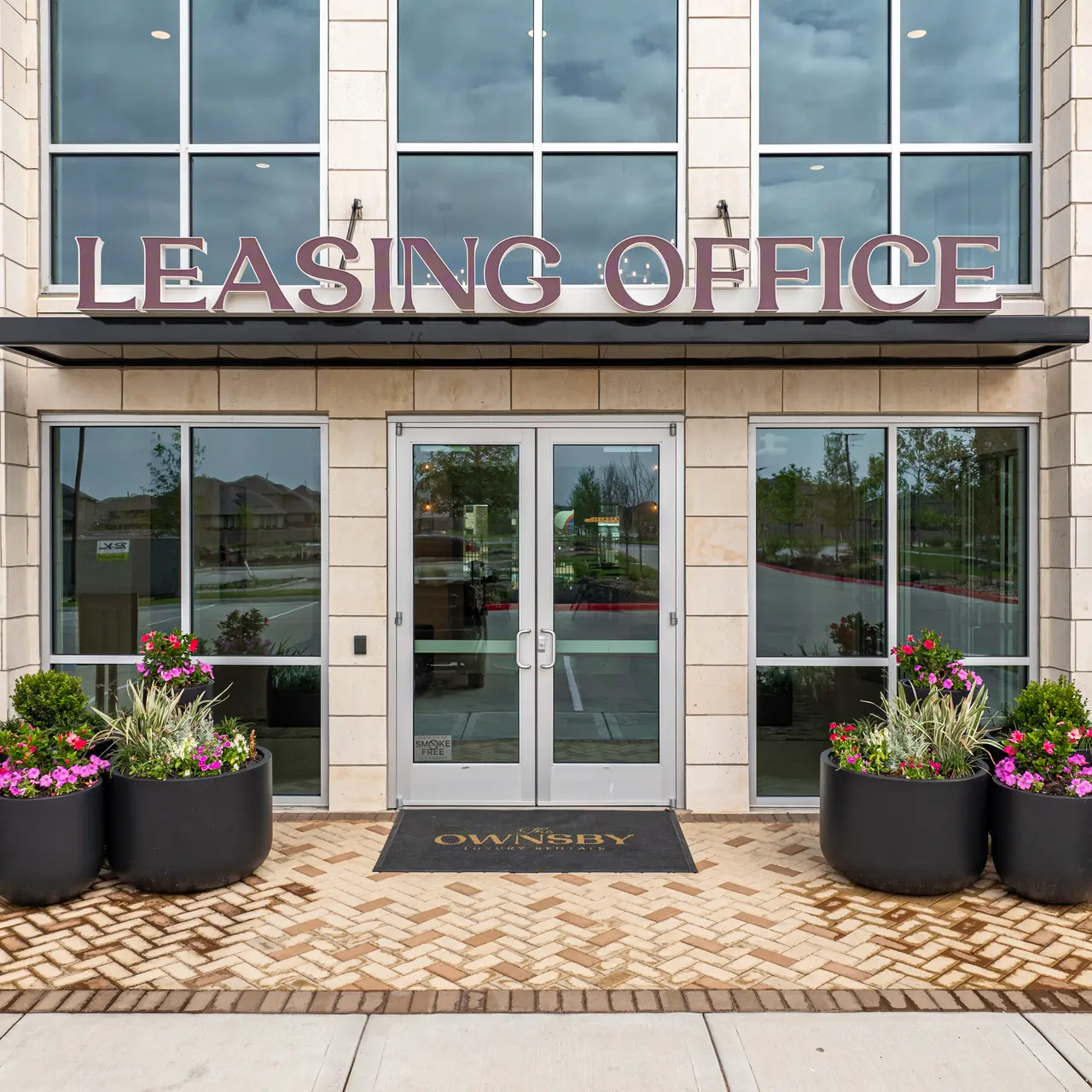 Leasing Office Entrance Exterior view of a leasing office with large glass doors and prominent signage.