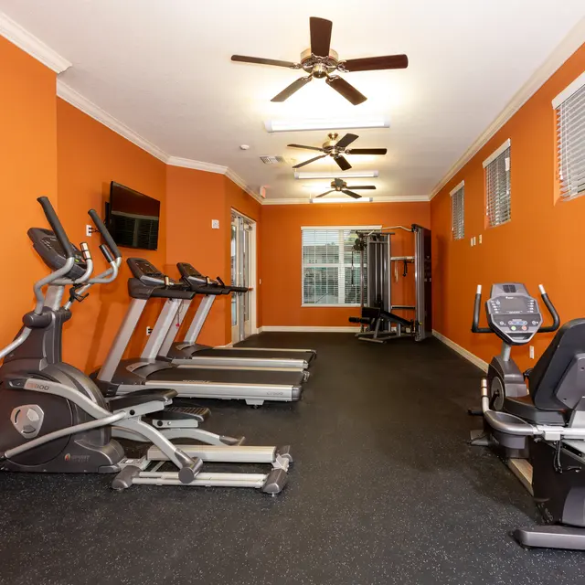 Interior view of a gym featuring exercise equipment and orange walls.