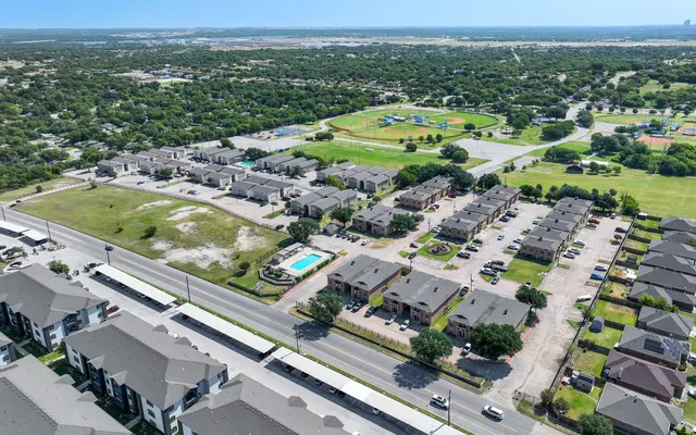 Aerial view of a residential area featuring apartment complexes, parking lots, and green fields.