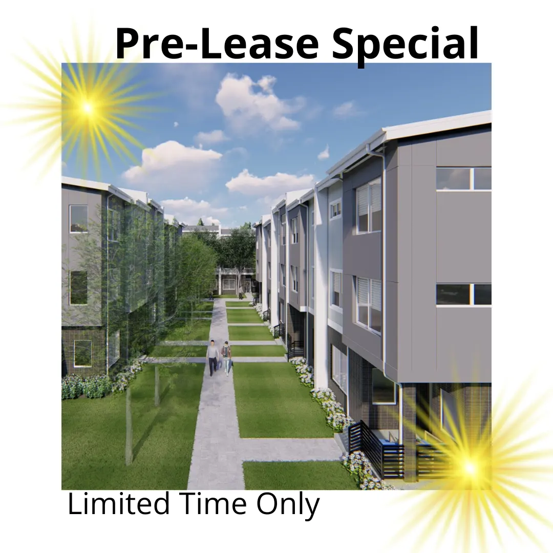 A modern residential complex with a landscaped pathway, green spaces, and contemporary buildings. The image features a clear blue sky and trees lining the pathway.