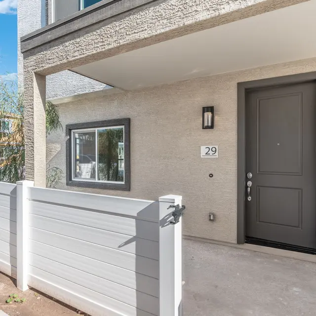 Modern Townhouse Entrance Exterior view of a modern townhouse entrance showing a gray door and white fence.