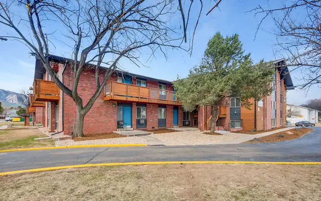 Exterior view of a two-story apartment complex surrounded by trees and landscaping.