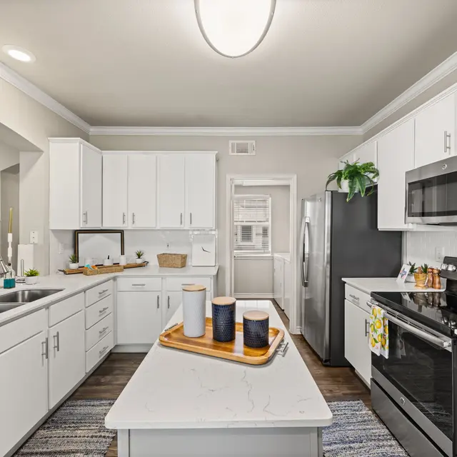 Modern Kitchen Interior A modern kitchen featuring white cabinets, stainless steel appliances, and a central island with decorative items on it.