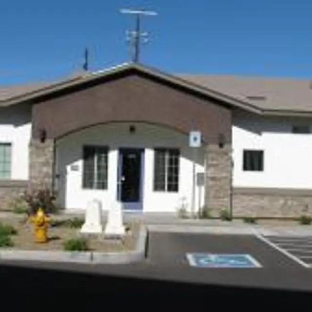 A modern community center building with a mix of stone and white exterior, featuring large windows and a central entrance.