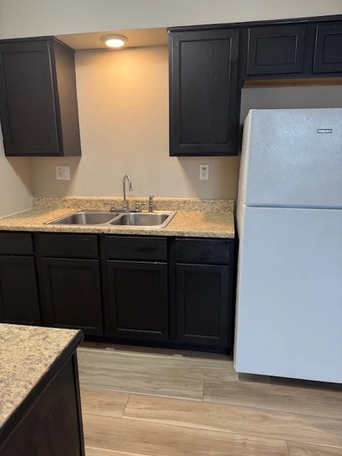 Modern Kitchen Design A modern kitchen featuring a dual sink, dark wooden cabinets, granite countertops, and a white refrigerator.