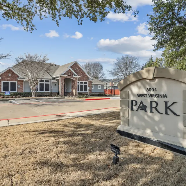 A well-maintained park entrance featuring a large sign that reads 'PARK' alongside a residential building.