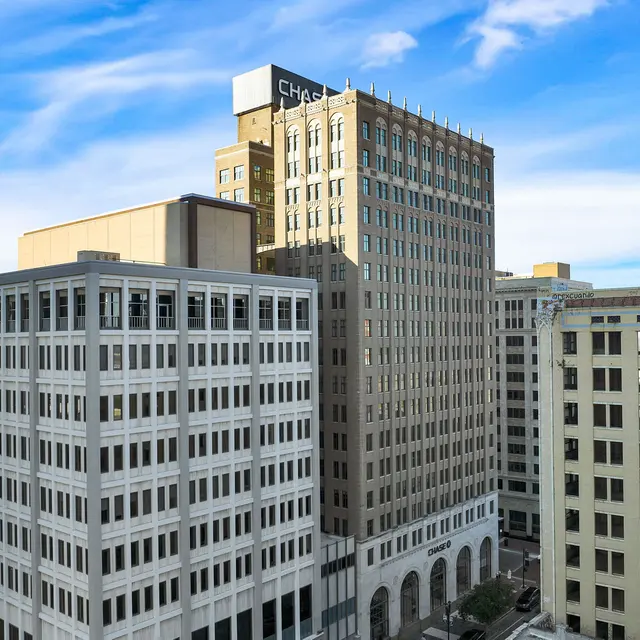 City Skyline with Modern and Historic Buildings A view of multiple city buildings against a blue sky with some clouds.