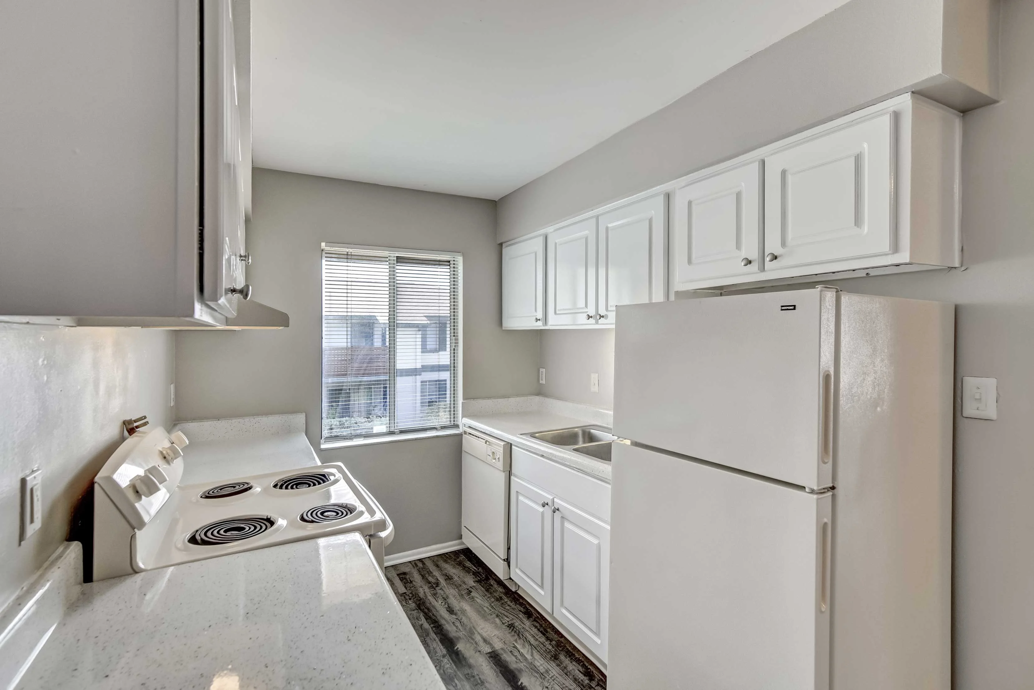 A modern kitchen featuring white cabinetry, a fridge, and a stove.