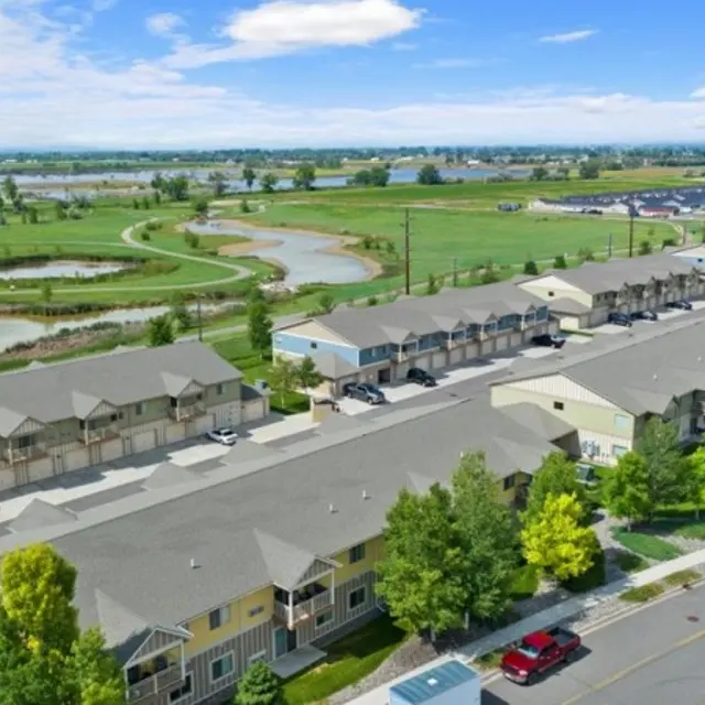 Granite Peak Aerial view of a housing complex with several buildings and green landscaping, near a body of water and open fields.