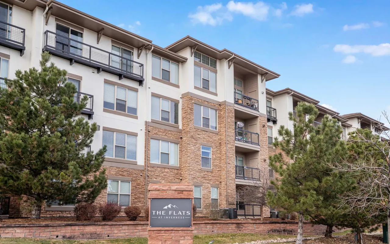 Exterior view of an apartment building named 'The Flats' with landscaped surroundings and balconies.