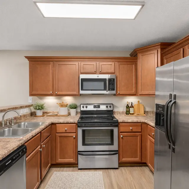 A modern kitchen featuring wooden cabinets, stainless steel appliances, and a spacious countertop with a sink.