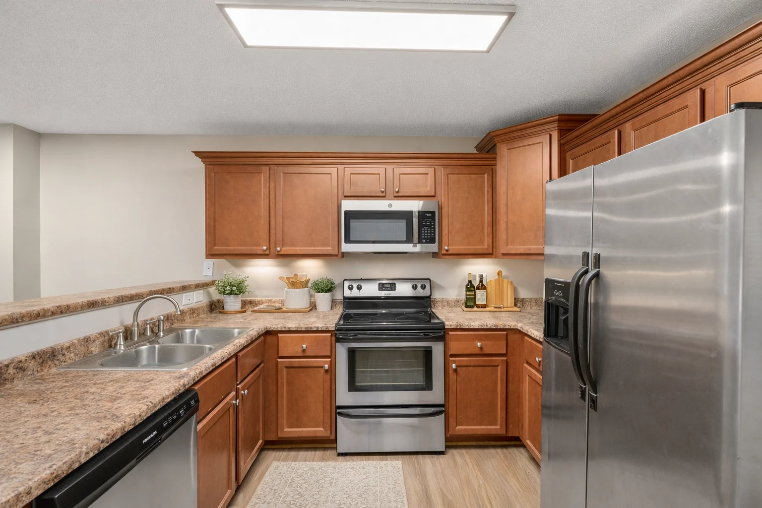 A modern kitchen featuring wooden cabinets, stainless steel appliances, and a spacious countertop with a sink.
