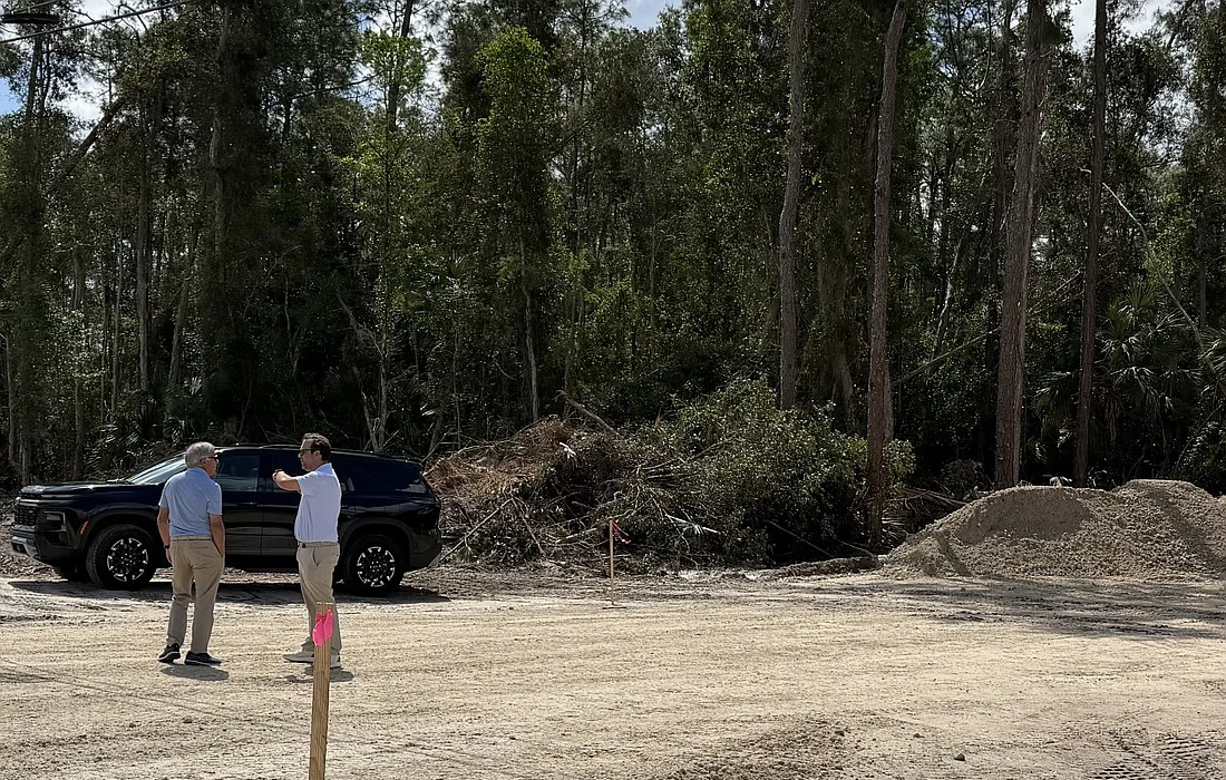 Site Meeting at Construction Area Two men discussing on a construction site with an SUV nearby and piles of dirt and debris in the background.