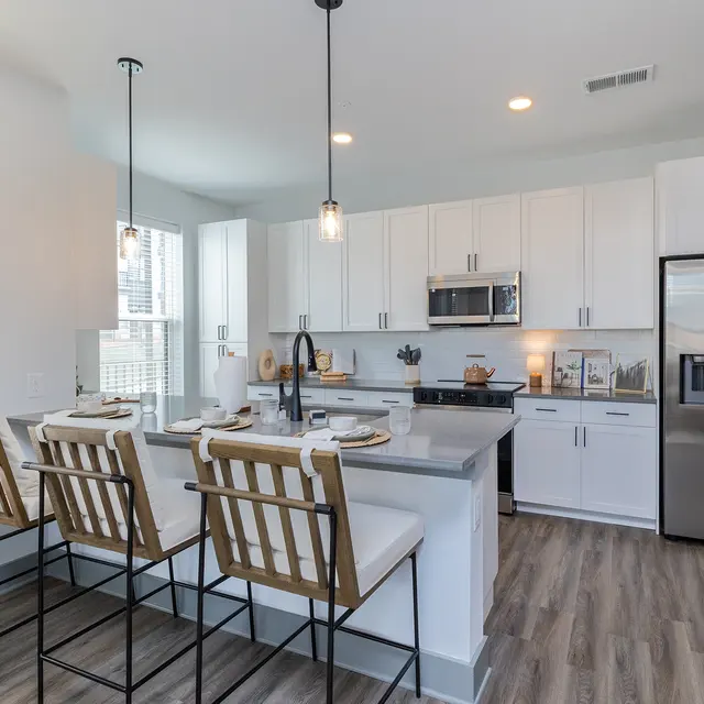 A modern kitchen featuring white cabinets, stainless steel appliances, and a large island with seating.