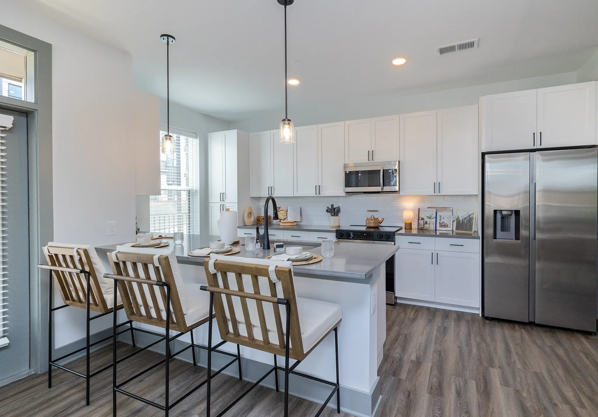 A modern kitchen featuring white cabinets, stainless steel appliances, and a large island with seating.