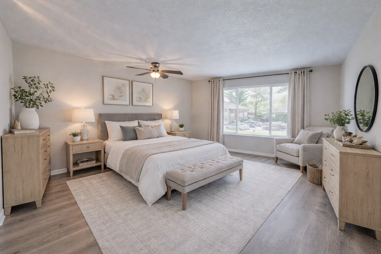 A modern bedroom featuring a light-colored bed with gray bedding, a spacious window with natural light, and wooden furniture including nightstands and a bench.