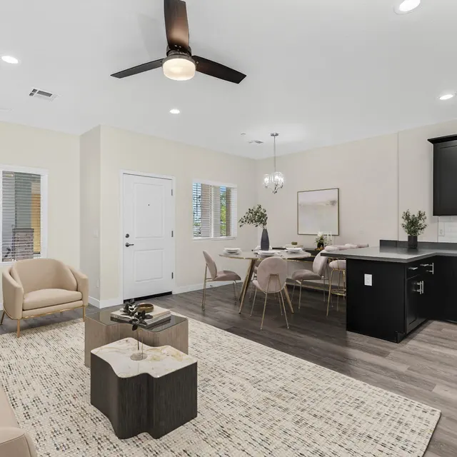 A modern and spacious living area featuring a light-colored sofa, a coffee table, and dining area with sleek furniture.