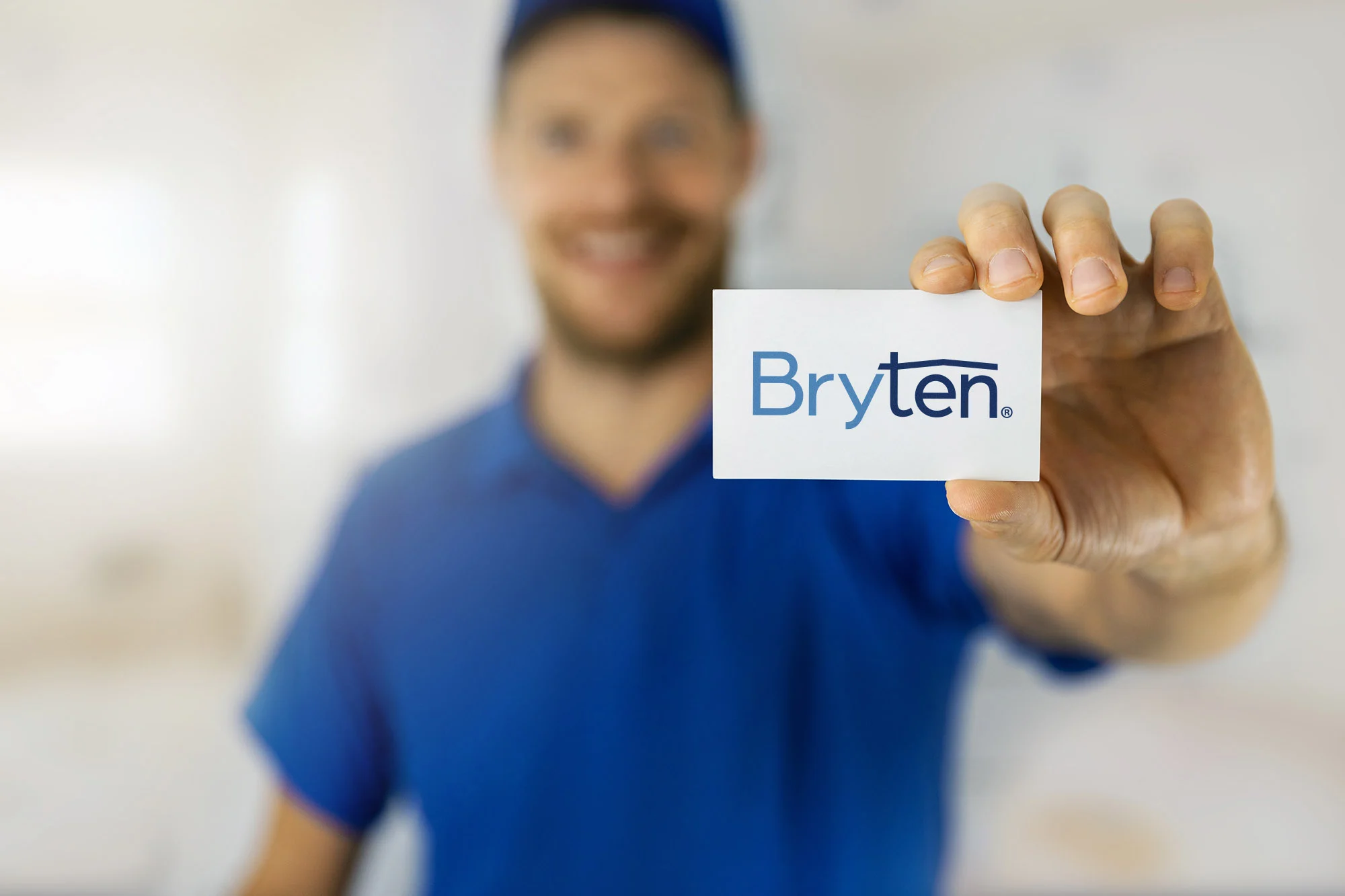 Bryten Business Card Representation A person in a blue shirt and cap holding up a business card with the logo 'Bryten' displayed prominently.