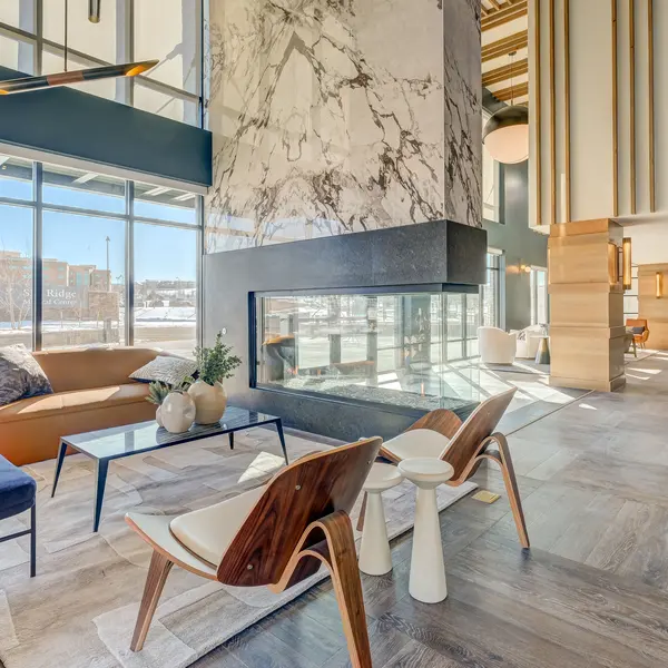 Modern living space with large windows, a stylish fireplace, and contemporary furniture. Light wood and marble accents create elegance.
