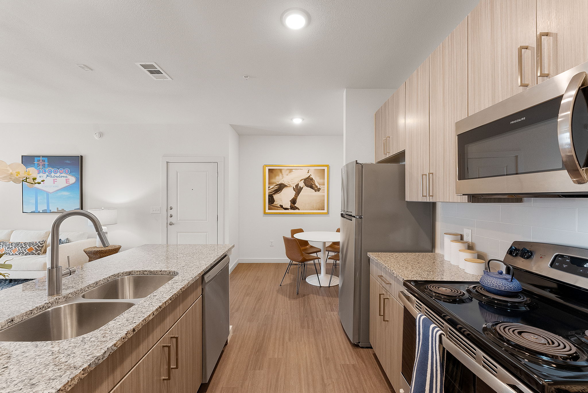 A modern kitchen featuring granite countertops, stainless steel appliances, and a dining area.