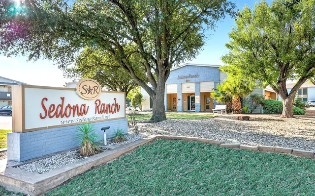 Sign for Sedona Ranch in front of a building surrounded by trees and grass.