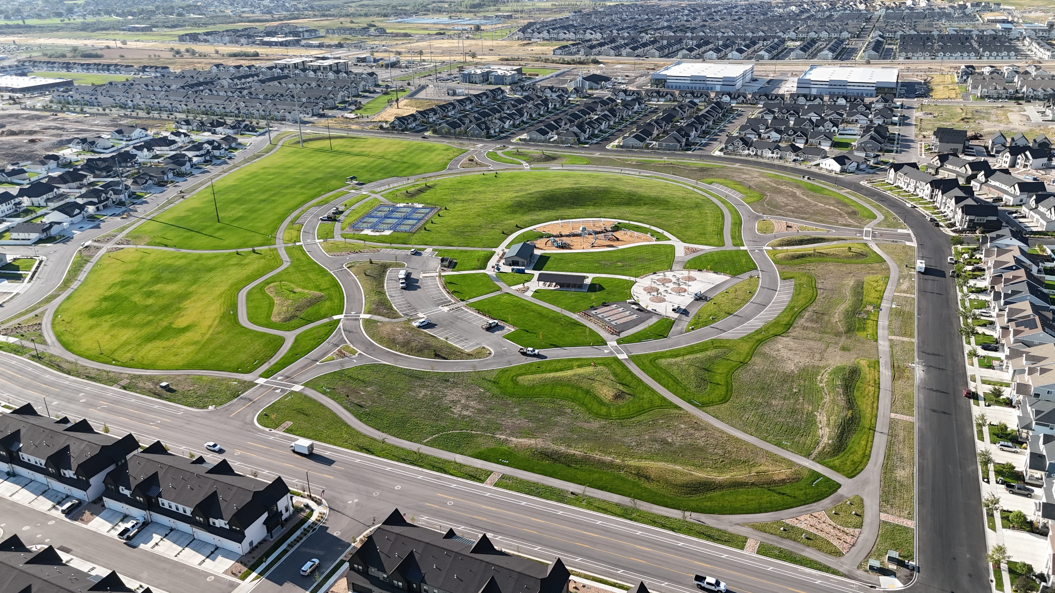 Aerial View of Suburban Park Aerial view of a large suburban park with green fields and playground areas, surrounded by residential streets and houses.