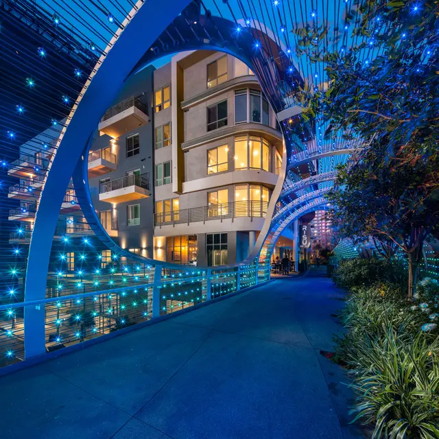 Illuminated Nighttime Walkway A picturesque nighttime walkway with glowing blue lights and modern apartment buildings in the background.