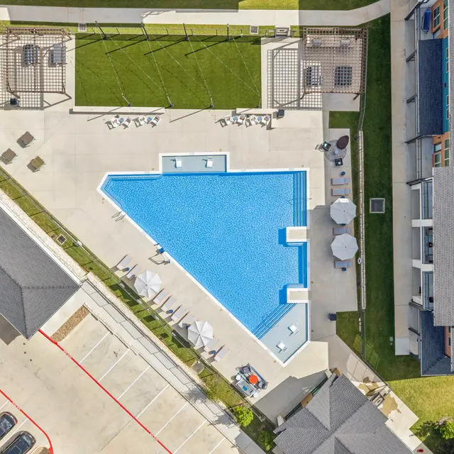 Community Pool Area Aerial view of a community swimming pool surrounded by grass and lounge areas.