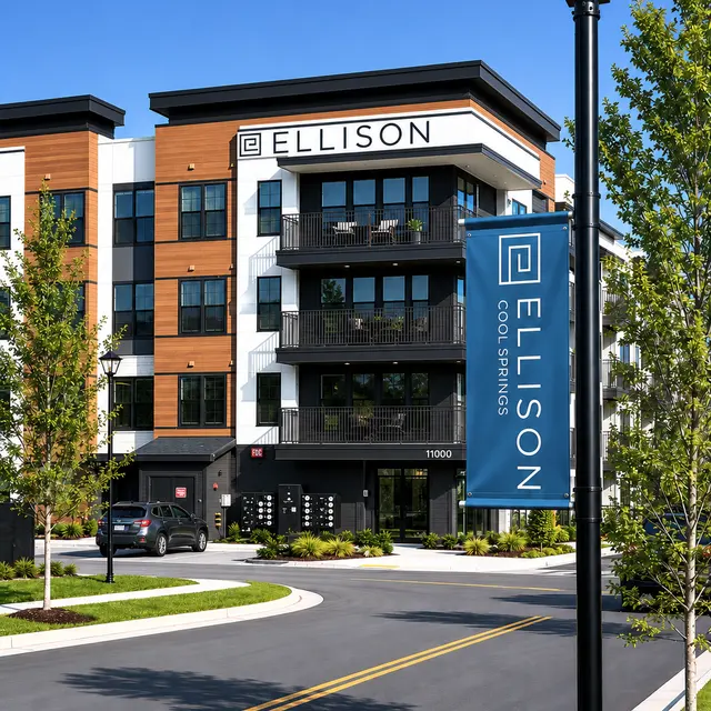 Modern apartment building with a banner that reads 'ELLISON' and landscaping around the entrance.