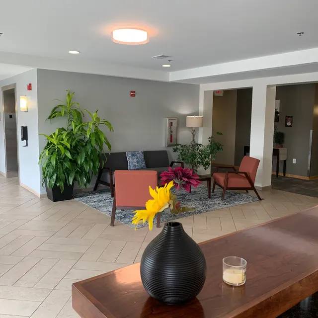A spacious lobby area featuring modern furniture, plants, and a reception desk.