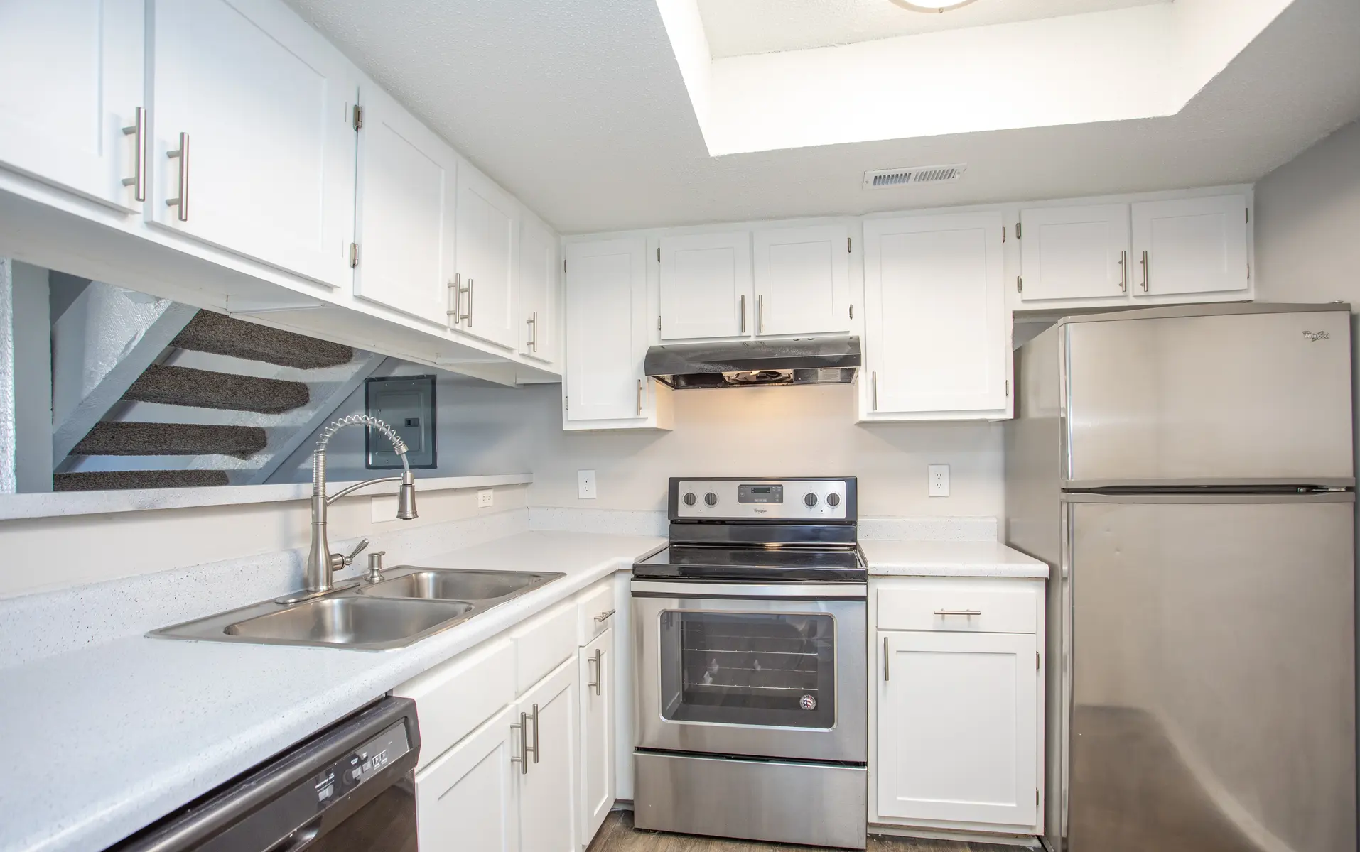 Modern kitchen with white cabinets, stainless steel appliances, and a double sink.