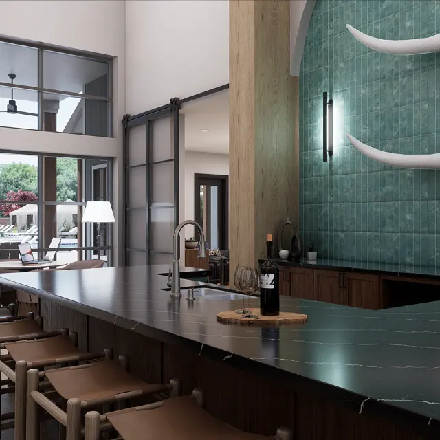 A modern kitchen featuring a long bar with beige seating, a sleek countertop, and two longhorn skulls mounted on a turquoise tiled wall. Large windows provide a view of a pool area outside.