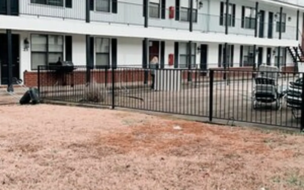 Apartment Complex Exterior View Exterior view of a two-story apartment complex with a grass lawn and parking area.