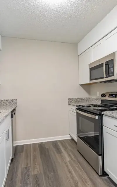 A modern kitchen featuring white cabinetry, stainless steel appliances, and granite countertops.