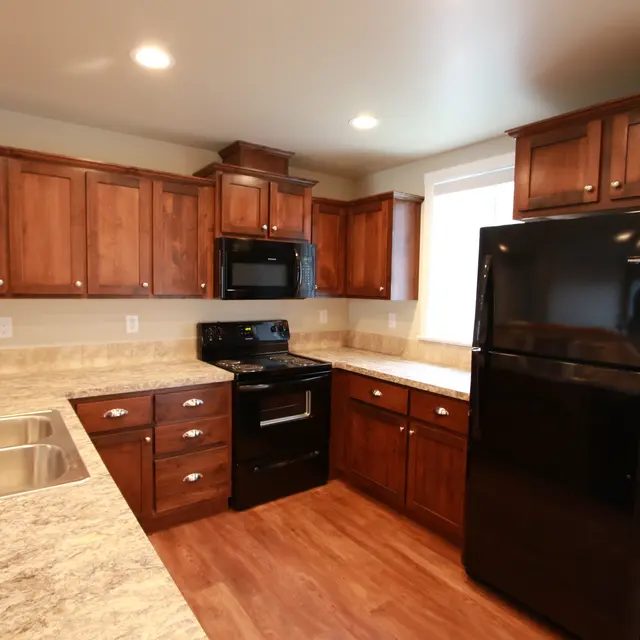 Modern Kitchen Design A modern kitchen featuring dark wood cabinets, a black refrigerator, and matching black appliances with a light-colored countertop.