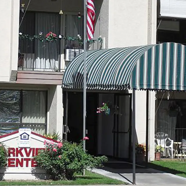 Parkview Center Entrance View of the Parkview Center building entrance with a striped awning and a sign in front indicating the name. An American flag is visible above the entrance.