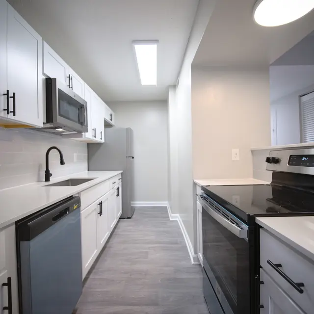 A modern kitchen featuring white cabinets, stainless steel appliances, and gray flooring.