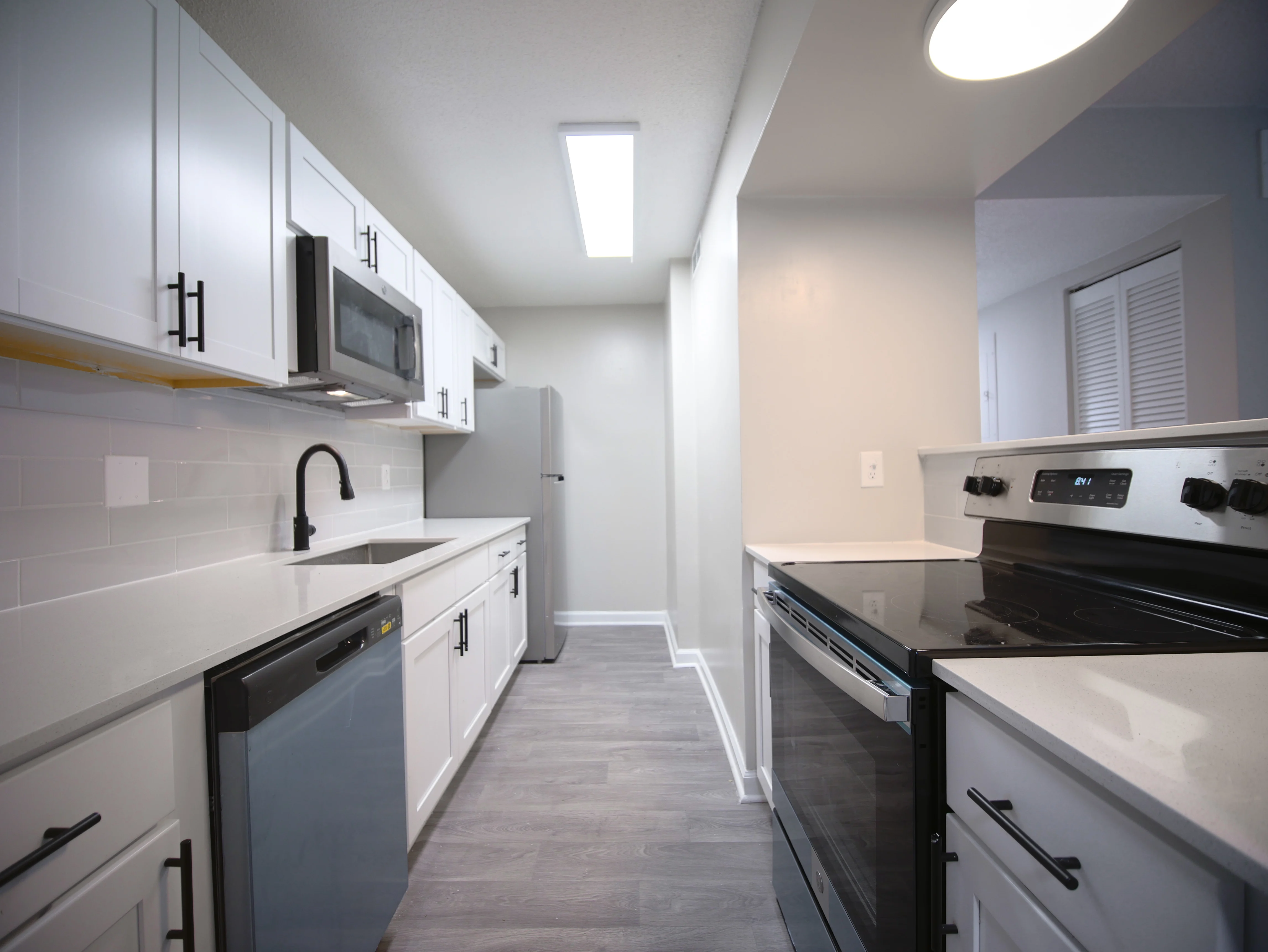 A modern kitchen featuring white cabinets, stainless steel appliances, and gray flooring.