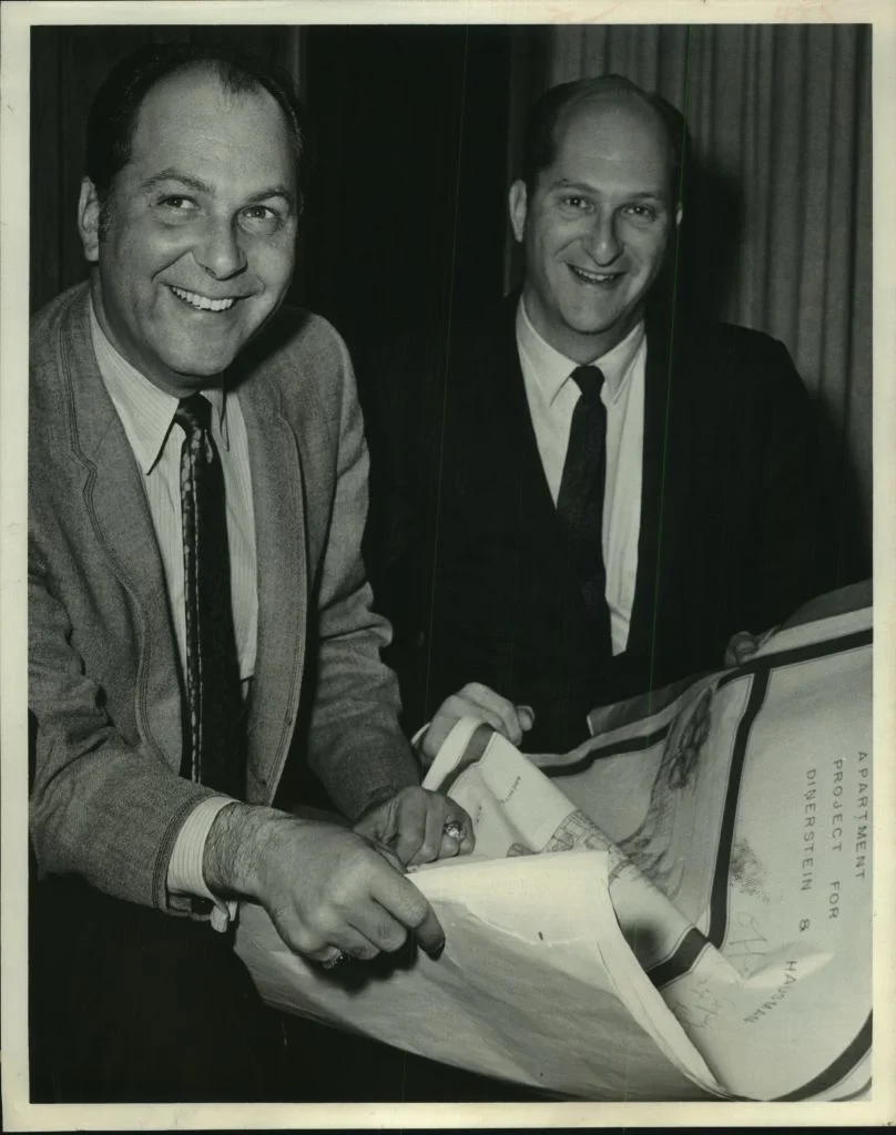 Men Holding Architectural Plans Two men smiling and holding large documents, possibly architectural plans, in a black and white photograph.