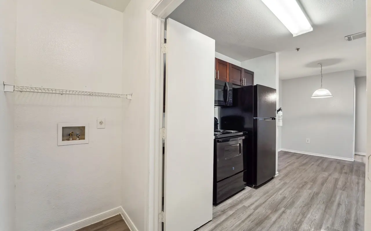 View of a small, modern kitchen with dark cabinets and appliances, featuring a space for a pantry or storage.