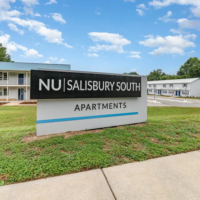 Sign for NU Salisbury South Apartments in front of a well-maintained complex with green lawns and blue skies.
