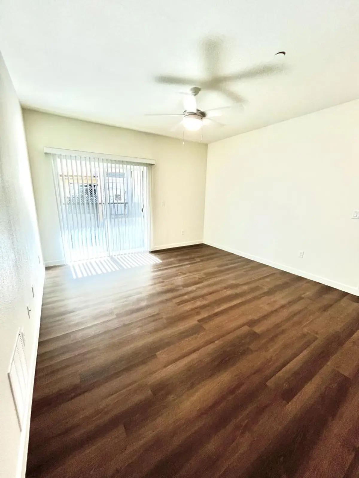 Living area with a ceiling fan and sliding glass door.
