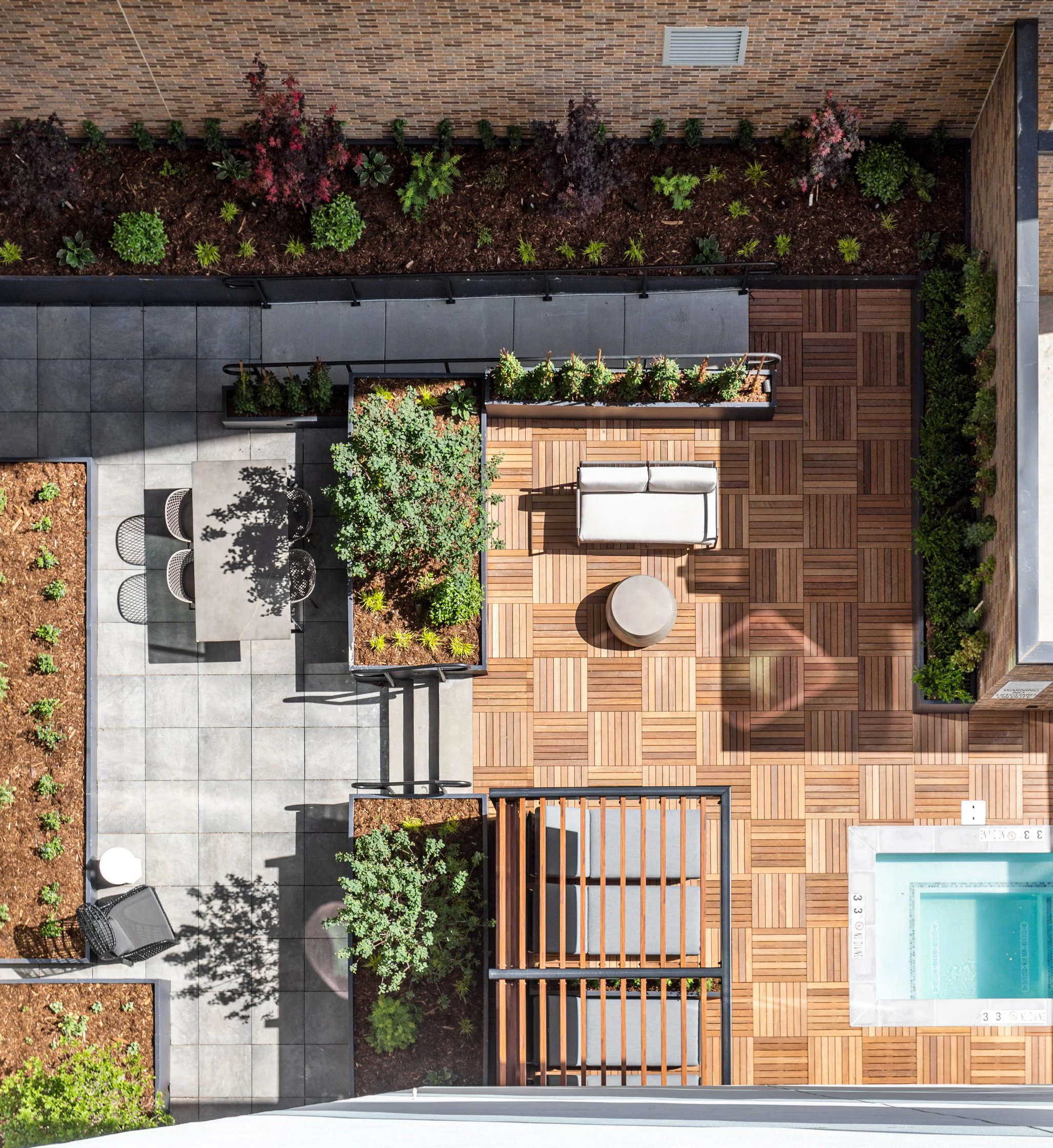 Modern Rooftop Garden and Pool An aerial view of a modern rooftop garden featuring a wooden deck, potted plants, a seating area, and a small pool.