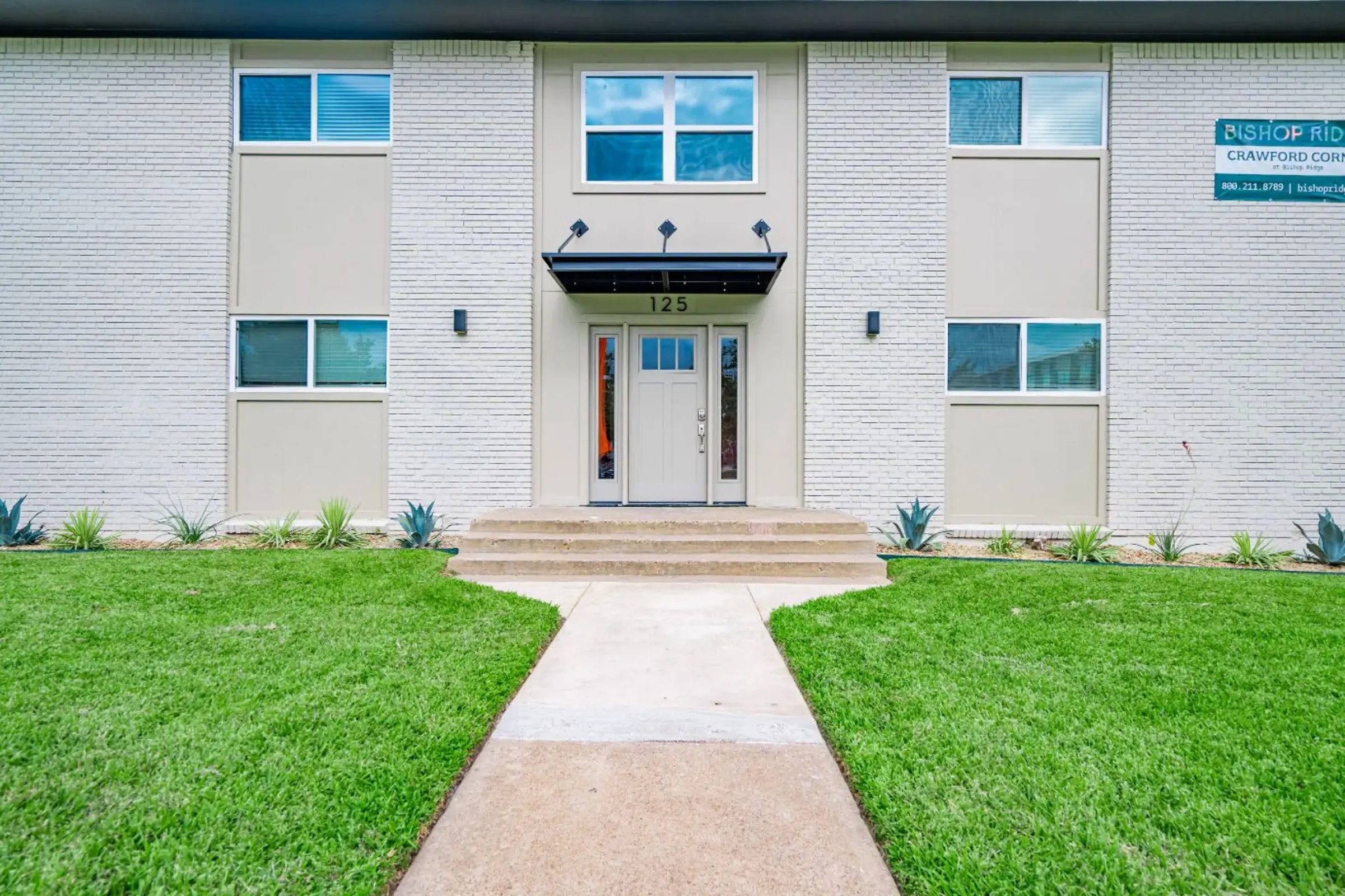 Modern Apartment Complex Entrance Front view of a modern apartment building with a clean exterior and landscaped lawn.